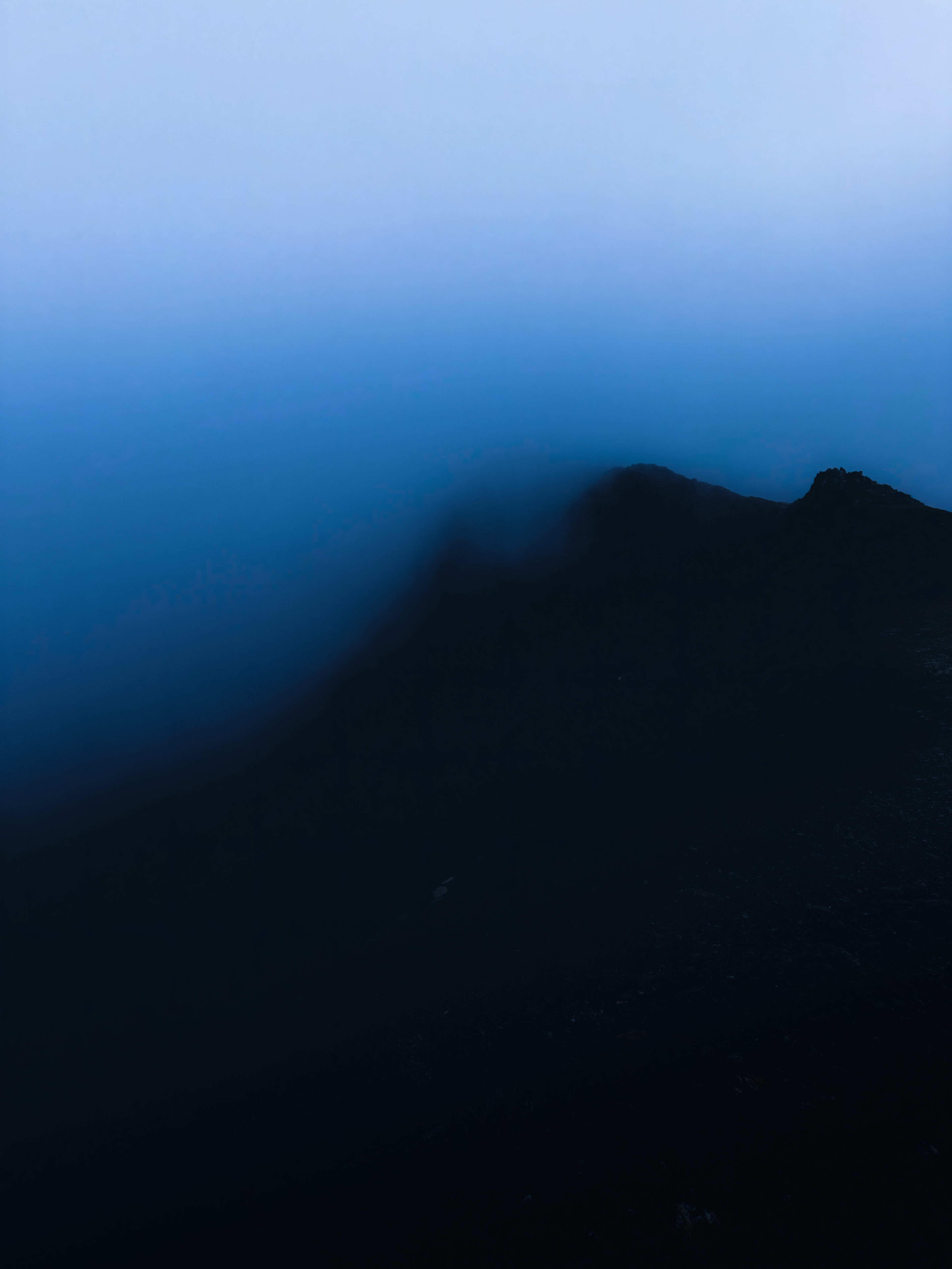 A jagged mountain ridge disappearing into soft blue mist