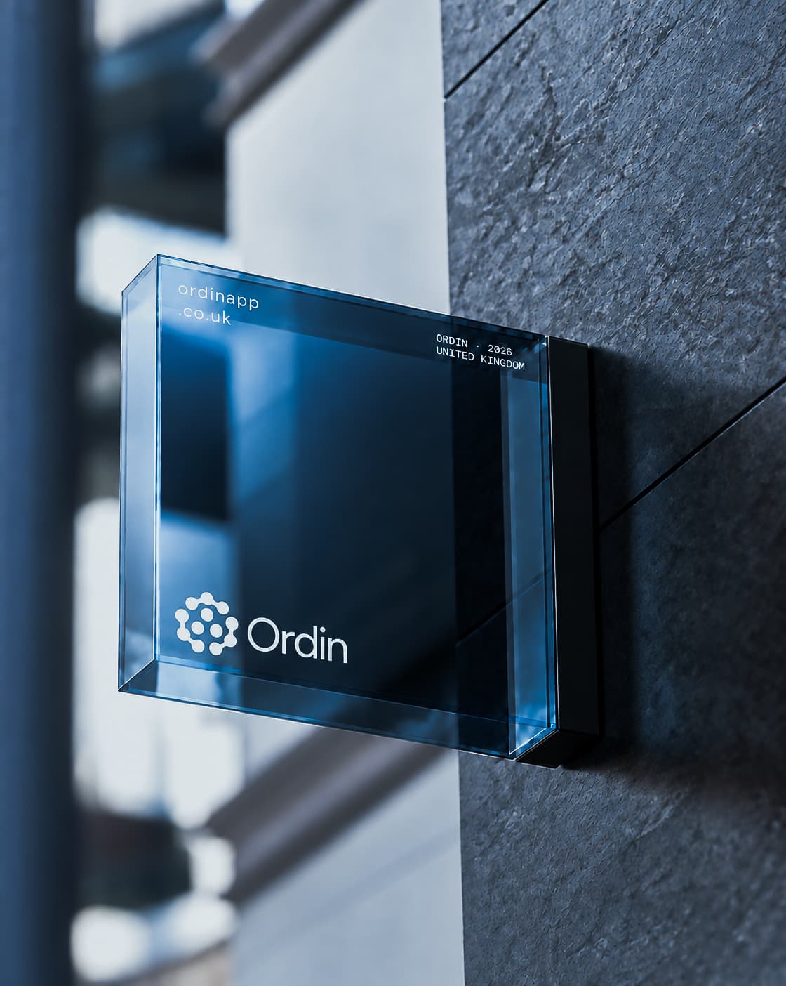 Ordin white emblem and wordmark on a blue glass wall sign in directional sunlight